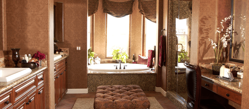 地中海式主浴室，装饰华丽的棕色墙壁，以及两个水槽柜台和一个粉末桌。还有一个可插入式浴缸，看起来很优雅。