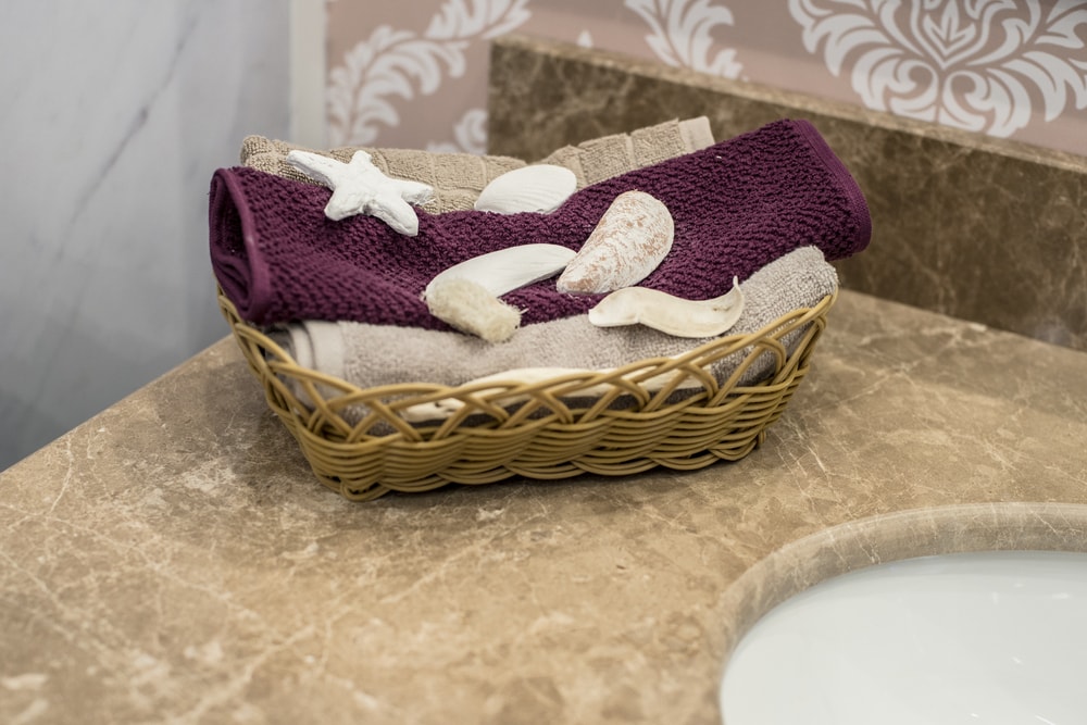 折叠的毛巾，上面有海星和贝壳，放在水槽上的篮子里。