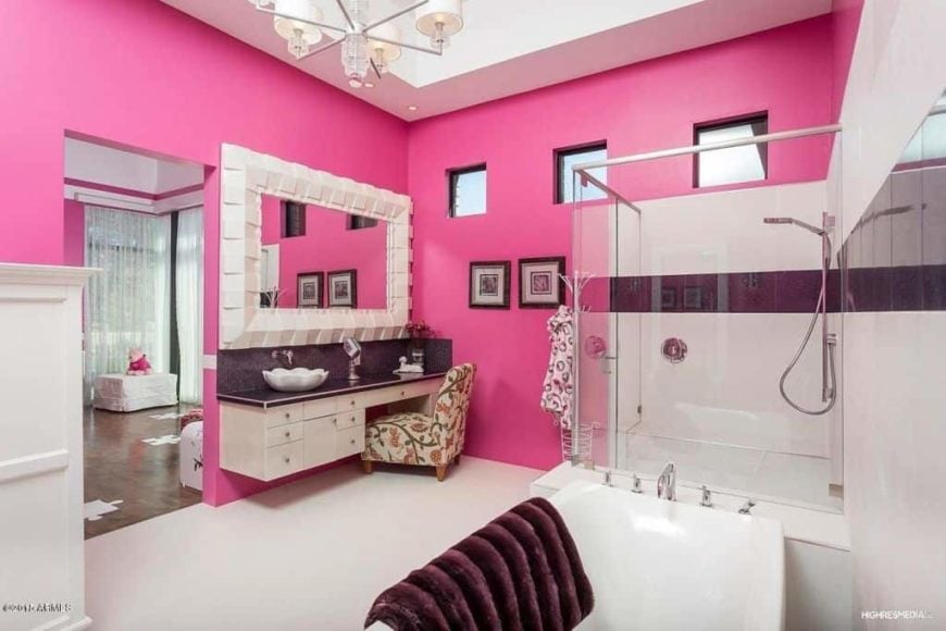 主要套房提供主要浴室，周围环绕着粉红色的墙壁。它有一个步入式淋浴区、一个独立浴缸、一个带水槽的浮动梳妆台、一张化妆台，天花板上有一盏可爱的枝形吊灯。
