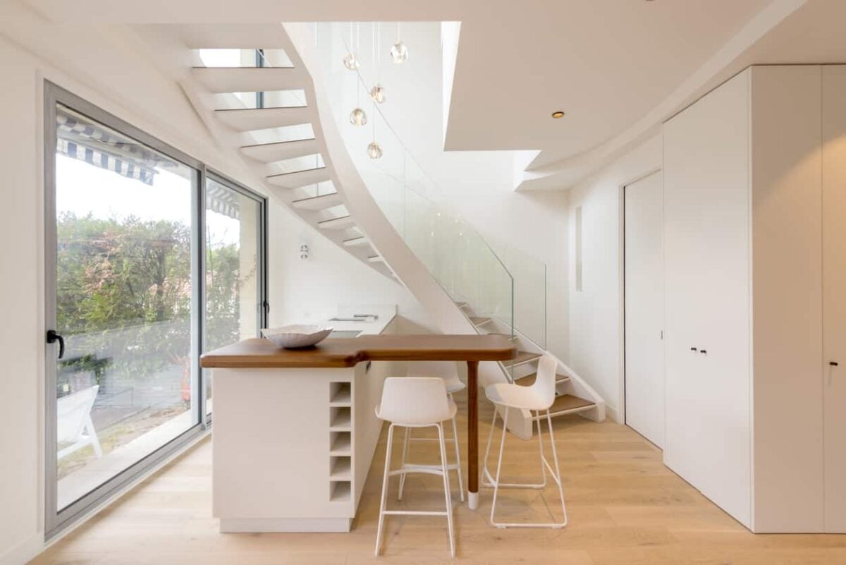 白色的小厨房靠近楼梯，面对着玻璃推拉门。