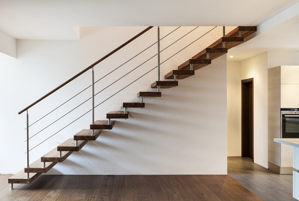笔直的楼梯以木制台阶为特色，带有金属立管支撑和电缆栏杆。该空间还包括与楼梯相匹配的硬木地板和嵌入式照明。