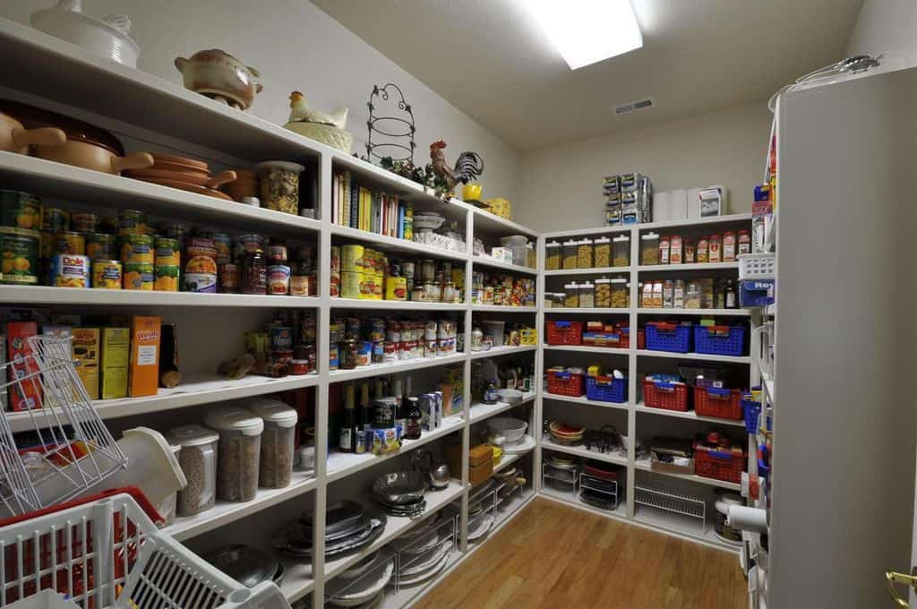 这是一个简单的步入式厨房食品储藏室，墙壁上摆满了浅灰色的食品储藏架。架子上还有色彩鲜艳的篮子，这些篮子与架子顶部的花色一起突出，作为小房间的装饰。