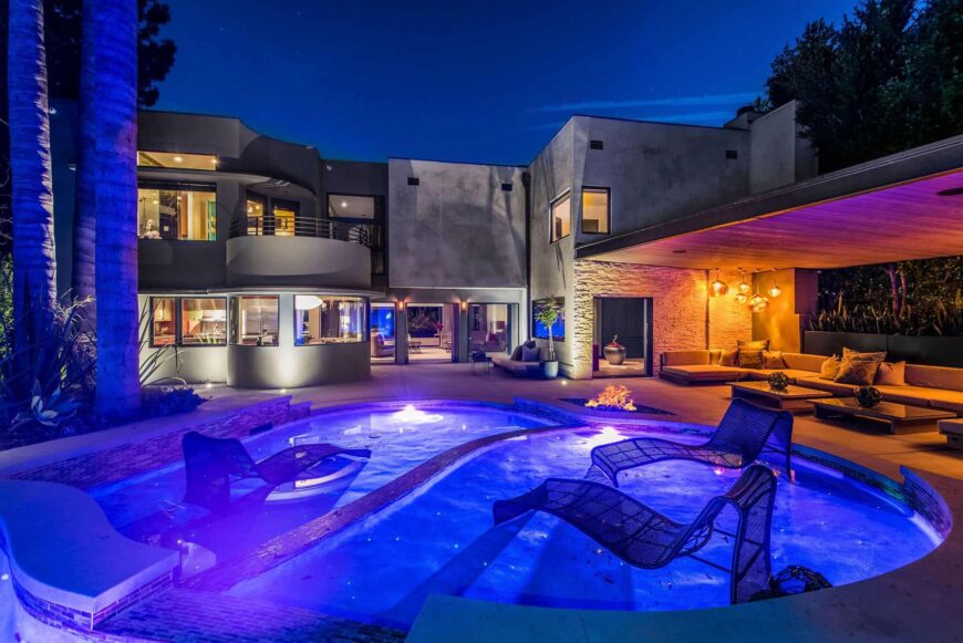 再看看室外定制游泳池和室外生活空间，这次是在灯光打开时面向房子。图片来自Toptenrealestatedeals.com。