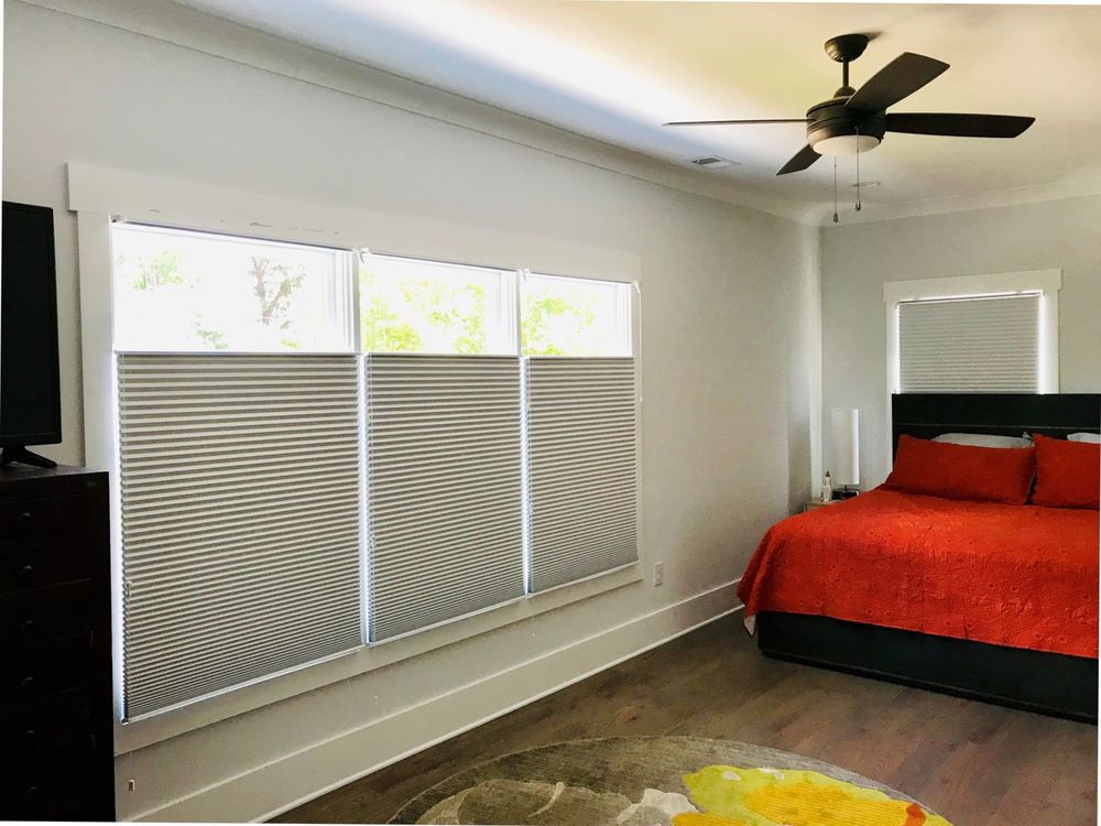 这间卧室的特色是硬木地板，灰色墙壁和常规天花板，以及带有窗帘的玻璃窗。