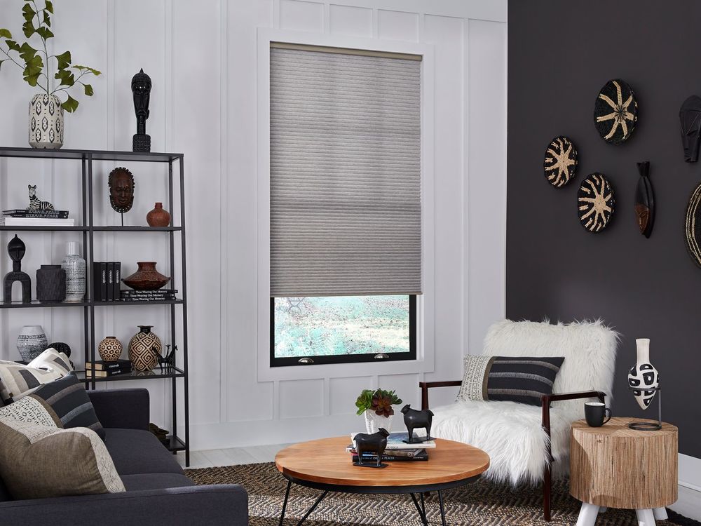 一个起居空间，配有现代沙发和时尚的中央桌子，以及黑白墙壁和带遮阳板的窗户。
