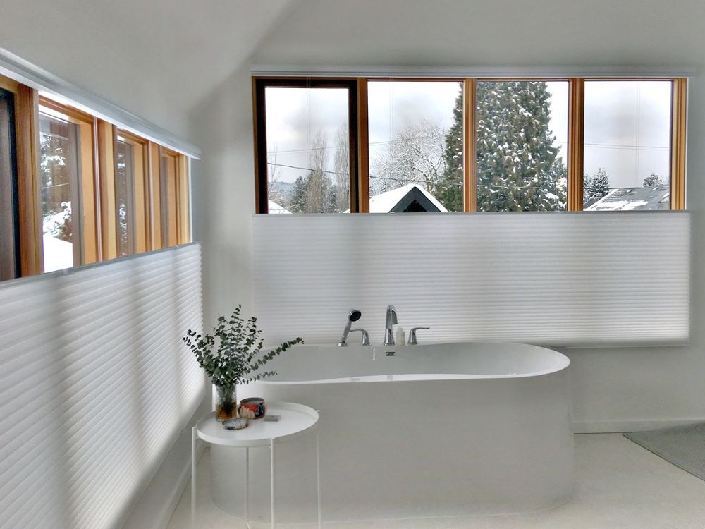 这间浴室拥有一个华丽的深泡浴缸，靠近窗帘覆盖的玻璃窗。