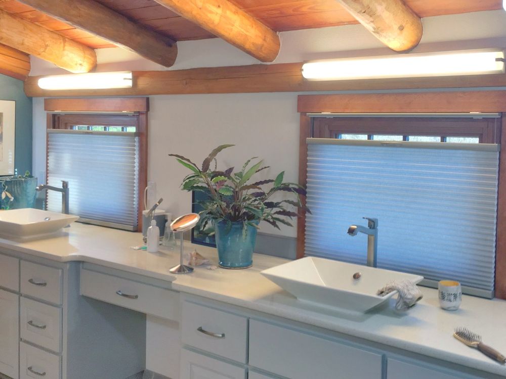这间浴室的特色是带有原木横梁的质朴天花板。它还有一个水槽柜台，中间有两个容器水槽和一个化妆台。