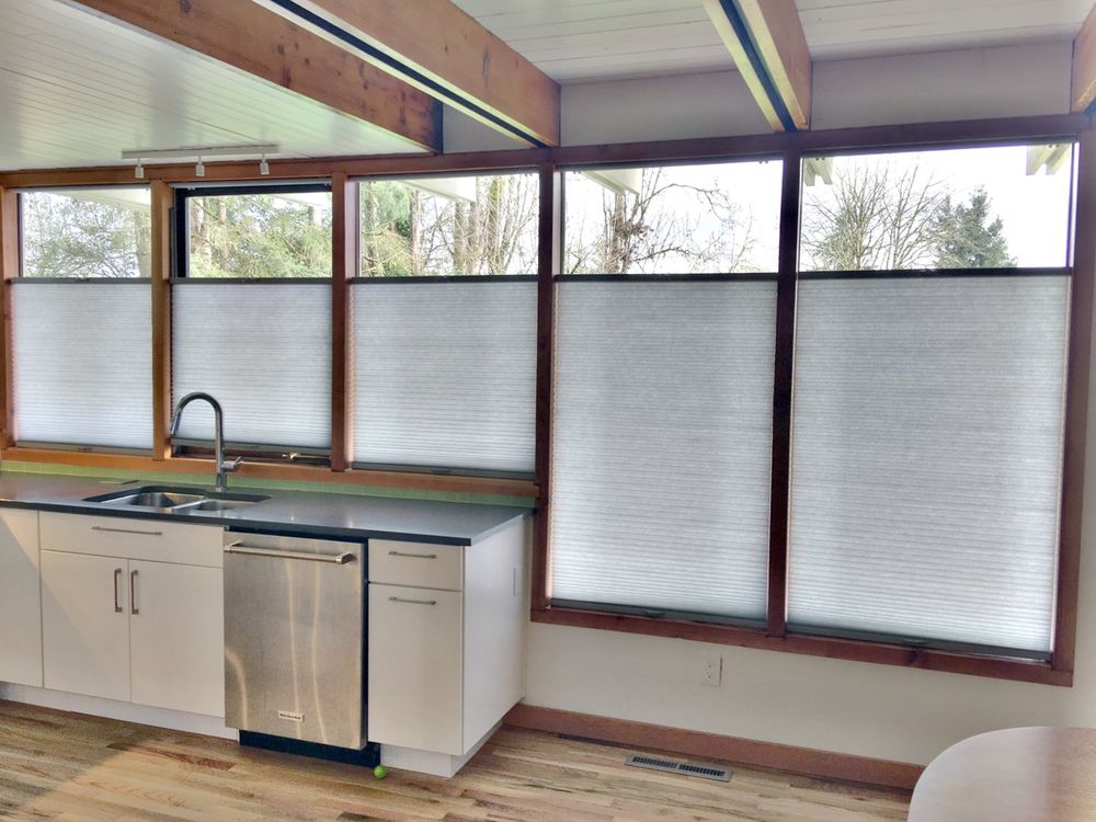 这间厨房设有硬木地板和带横梁的天花板。它还设有带遮阳帘的窗户。