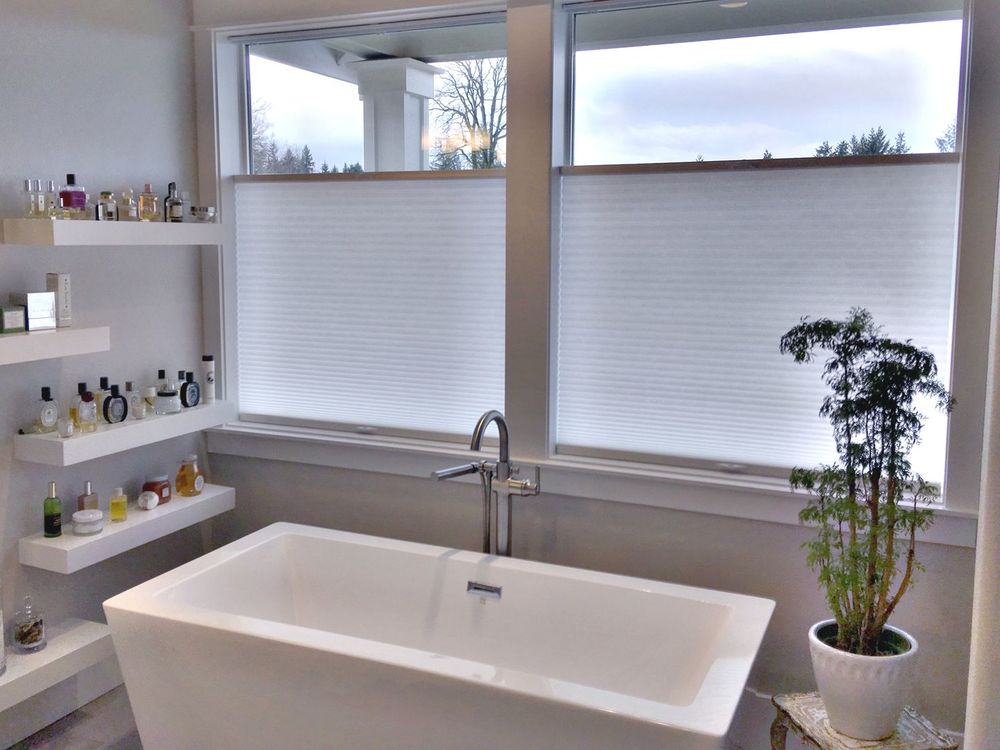 主浴室设有独立的深泡浴缸和侧面的内置架子，以及带窗帘的玻璃窗。