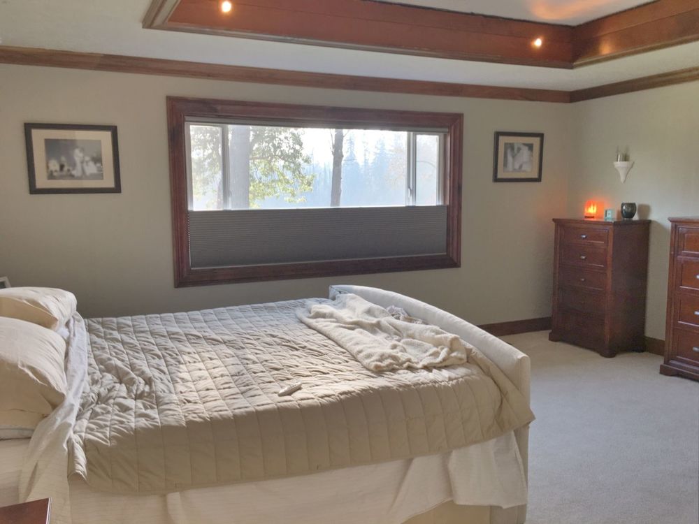 这间卧室提供一张舒适的床以及带窗帘的玻璃窗。房间里还有地毯地板和迷人的托盘天花板。