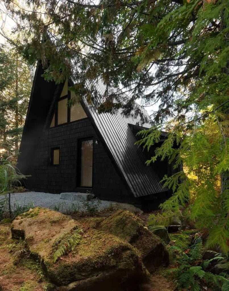 这个独特的房子有一个小屋风格的景观，似乎把自己与周围的动物结合起来，充满了高大的树木，苔藓和大岩石。有一条砾石走道通向大门，在那里你可以踩在一块大石板上。