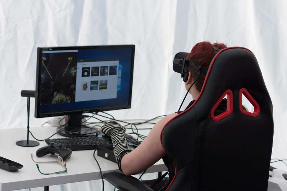 一个人坐在游戏椅上玩VR的后视图。