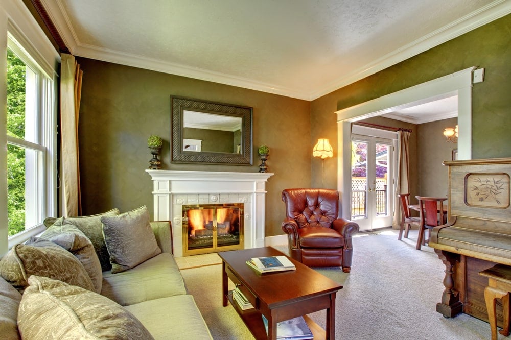 绿色客厅，配有老式钢琴，传统壁炉和地毯地板。