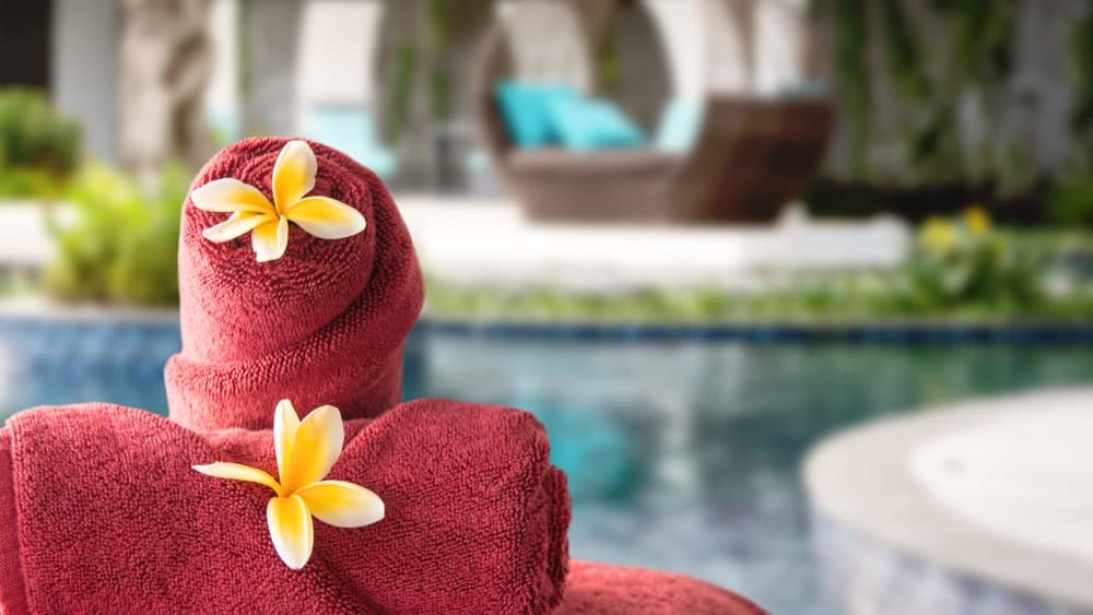 红色卷毛巾，上面有一个花瓣在户外度假村设置。
