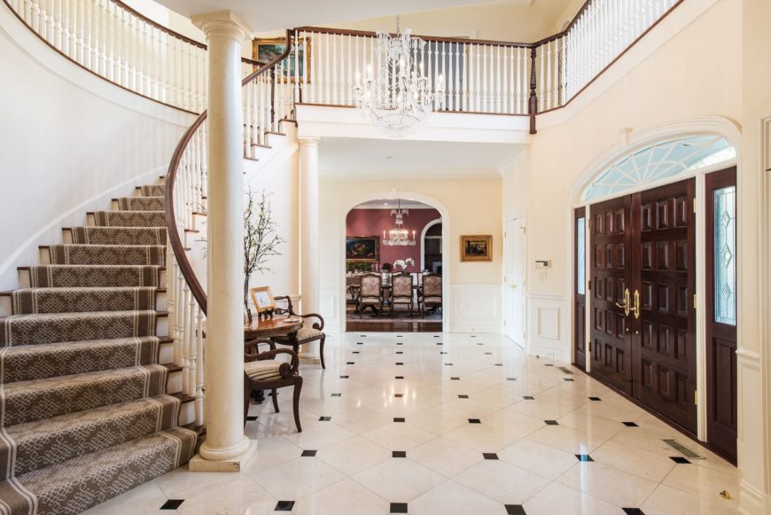 房子的门厅有一个华丽的弯曲楼梯，地板铺着地毯。该区域还铺设了优雅的瓷砖地板，两层楼高的天花板由一盏别致的枝形吊灯照亮。图片来自Toptenrealestatedeals.com。