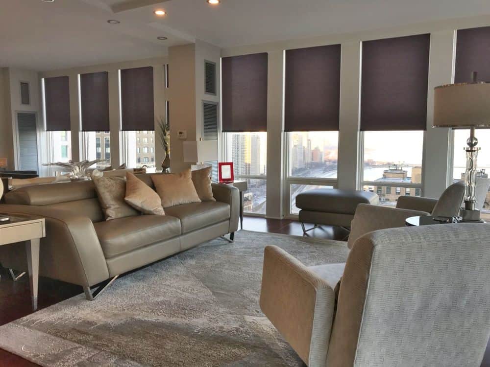 宽敞的起居空间，配有现代沙发套装和覆盖硬木地板的大面积地毯。房间周围的窗户也有窗帘。