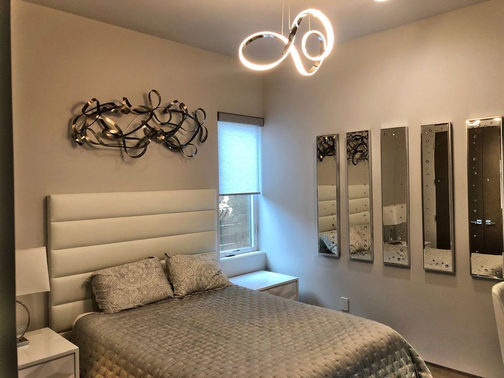 这间卧室提供舒适的床上用品和引人注目的墙壁装饰和天花板照明。