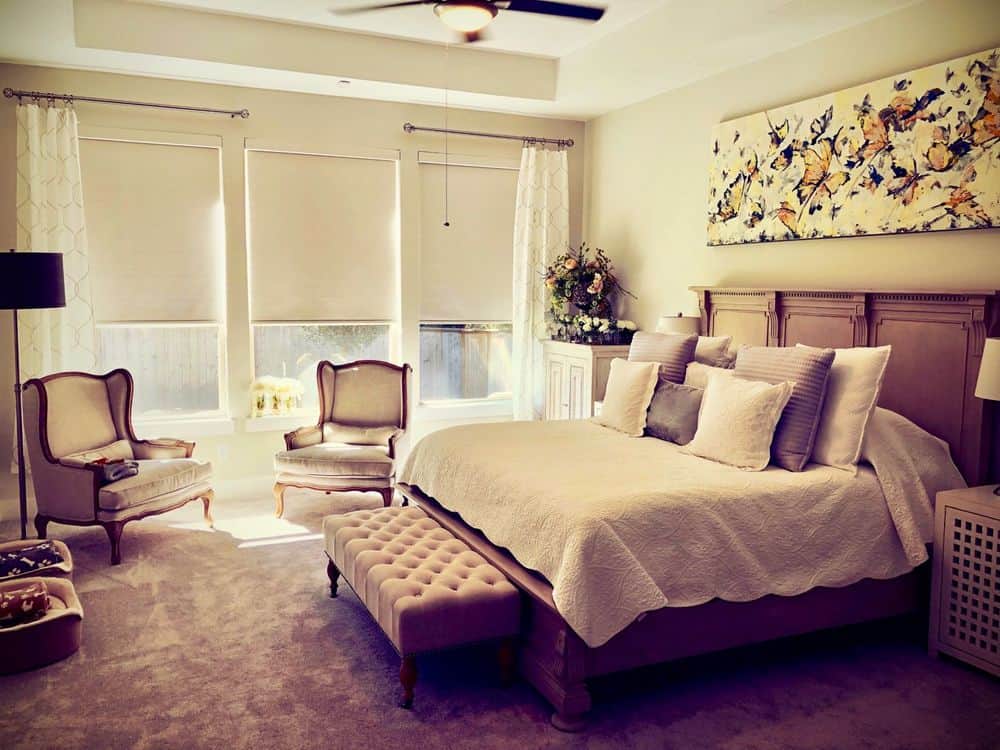 主卧室拥有一张优雅的大床和一侧的休息区。房间设有地毯地板和托盘天花板，以及带窗帘的玻璃窗。
