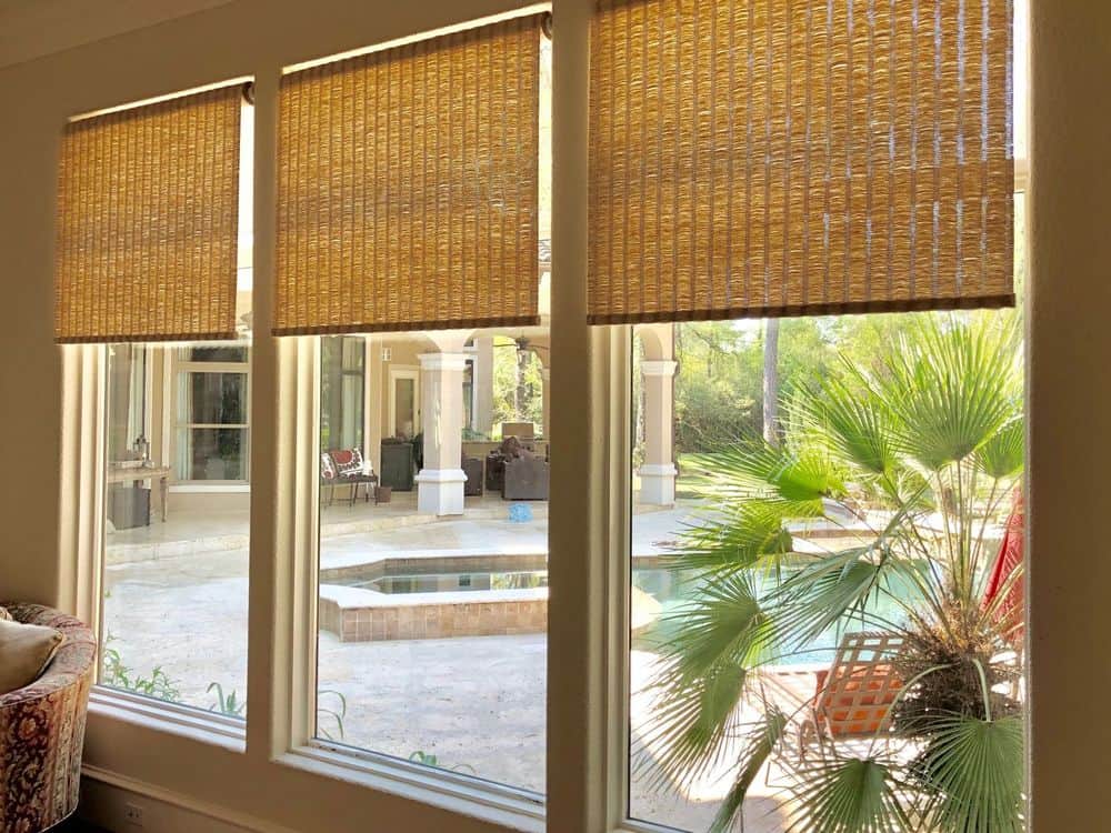 专注地看这个家的现代玻璃窗，设有木制窗帘。透过窗户可以看到可爱的户外区域。