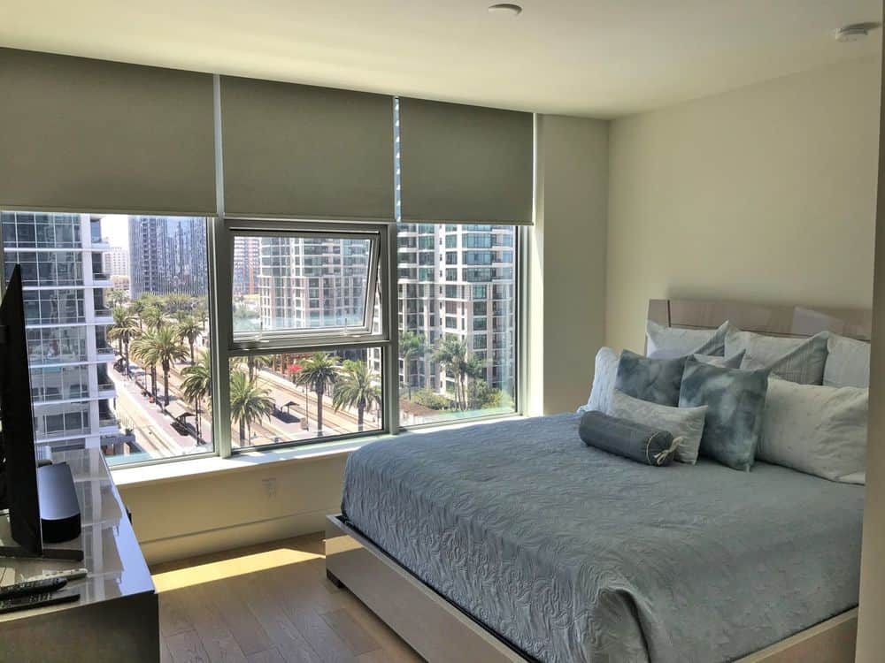 这间卧室提供一张舒适的现代床，前面有一台宽屏电视机。玻璃窗还设有窗帘。