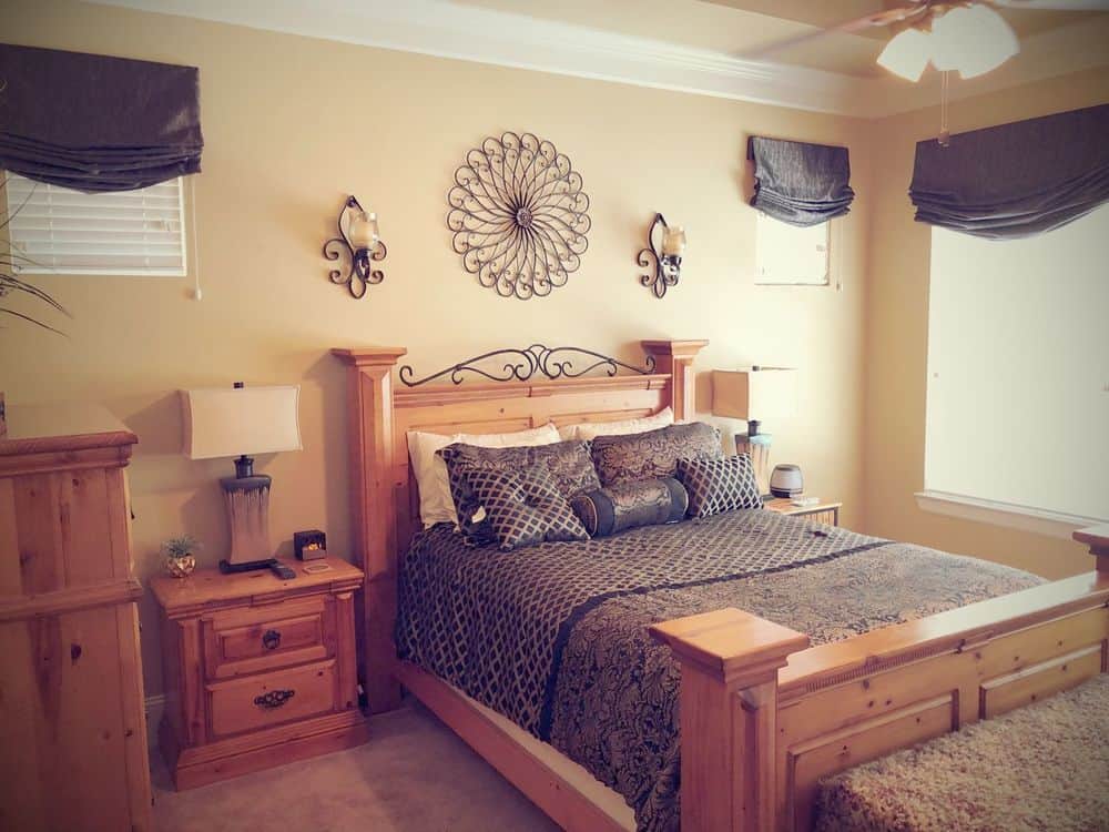 主卧室提供一张木框大床，一个木边桌和一个木柜子。房间有米黄色的墙壁，托盘天花板上有华丽的天花板照明。