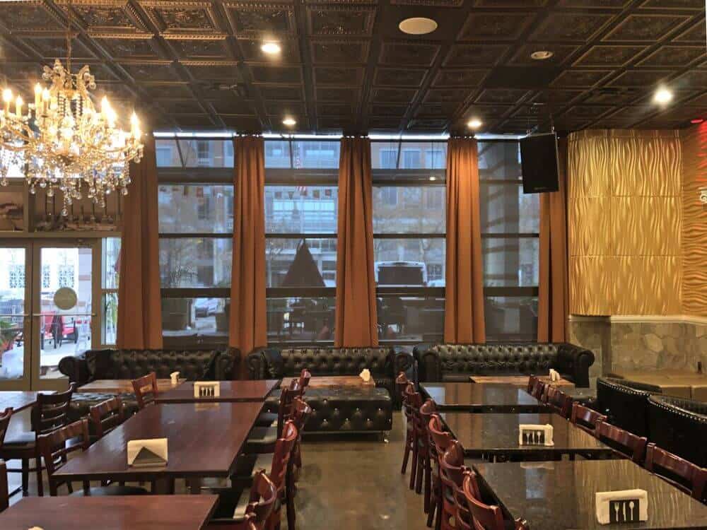 一个美丽的餐厅拥有优雅的餐桌和优雅的黑色皮沙发。该建筑拥有一个定制的装饰天花板，由一个迷人的吊灯照亮。