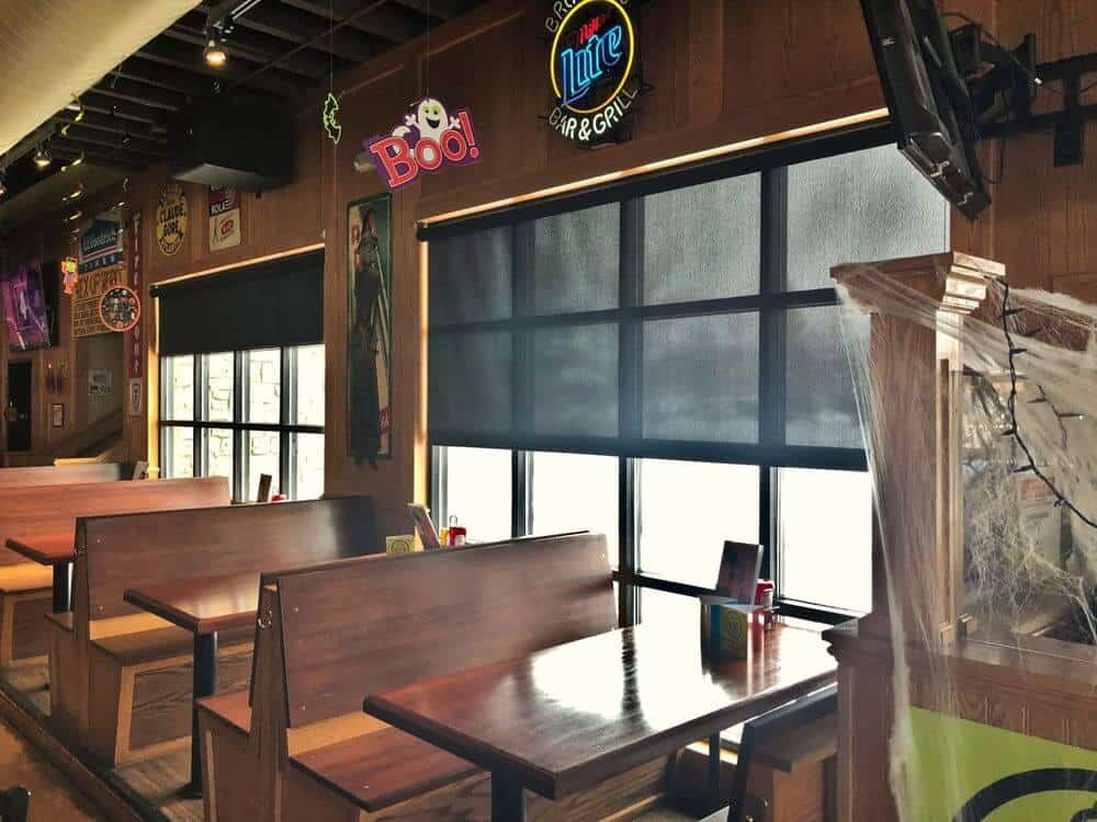 餐厅拥有时尚的餐桌套装，定制天花板和带有太阳能窗帘的窗户。