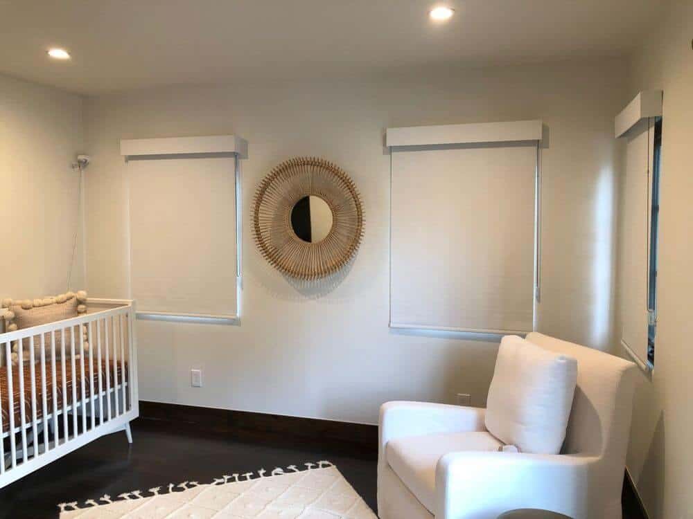 一间育婴室设有深色硬木地板和白色墙壁，以及带有嵌入式顶灯的常规天花板。