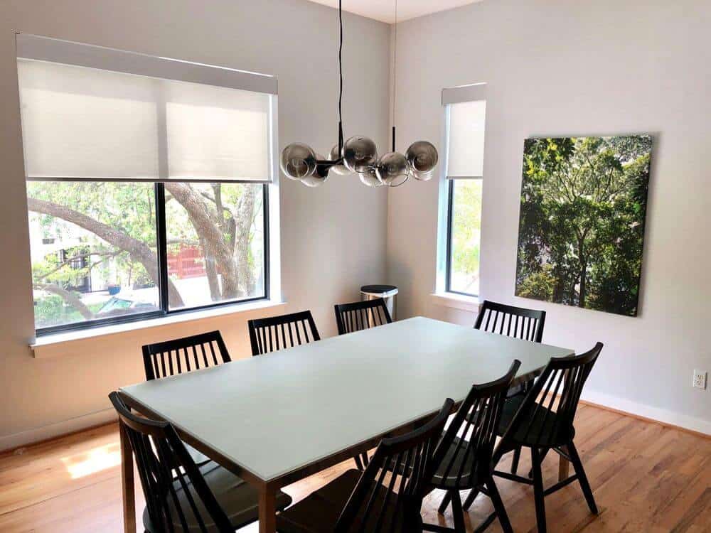 该住宅提供了一个餐厅，设有一个时尚的餐桌，由一个时尚的天花板灯照明。房间的特色是白色的墙壁和带遮阳板的玻璃窗。