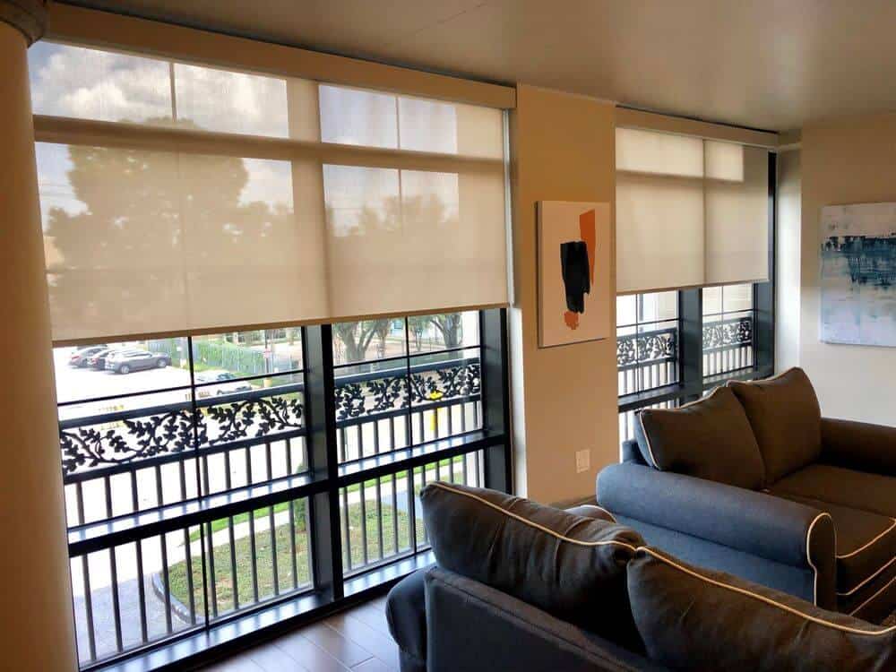 生活空间设有现代沙发，周围环绕着米色墙壁和硬木地板。该区域有大玻璃窗，设有窗帘。