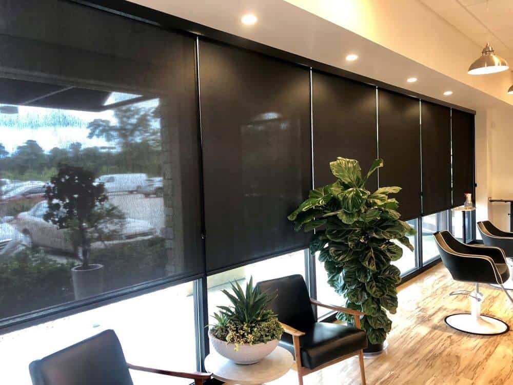 大型办公室拥有大型玻璃窗，设有黑色太阳能窗帘，现代座椅和定制天花板。