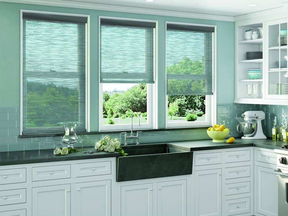 这间厨房设有一个l形的厨房柜台，带有绿色瓷砖后挡板和绿色墙壁，以及白色的橱柜和搁架。该区域的窗户还设有时尚的遮阳板。