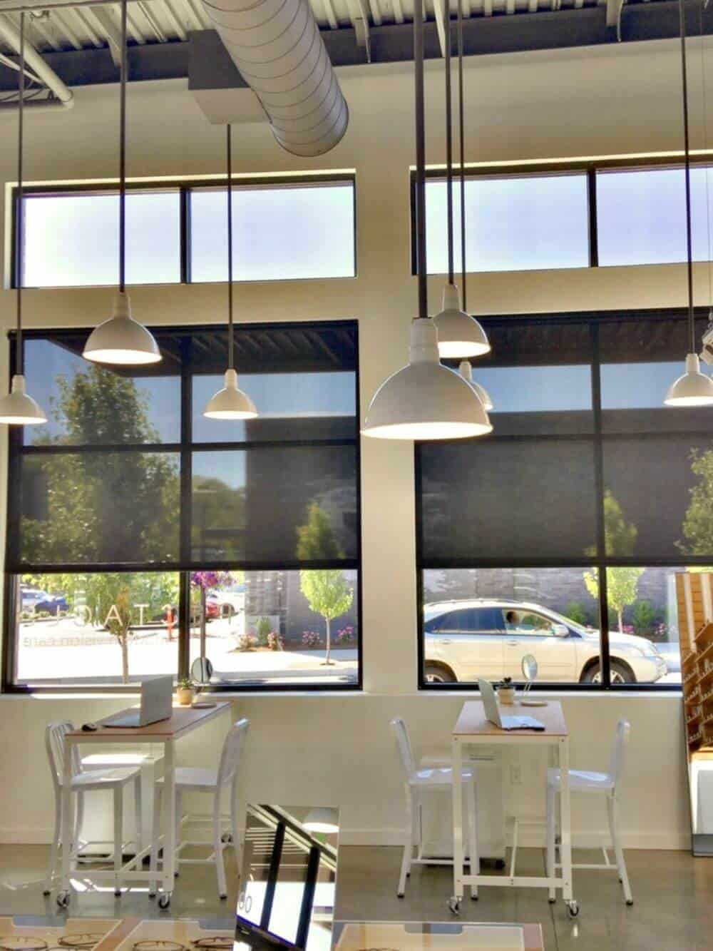 餐厅的用餐区设有多个餐桌和一个带有几个吊灯的高高的天花板。有玻璃窗，也有遮阳板。