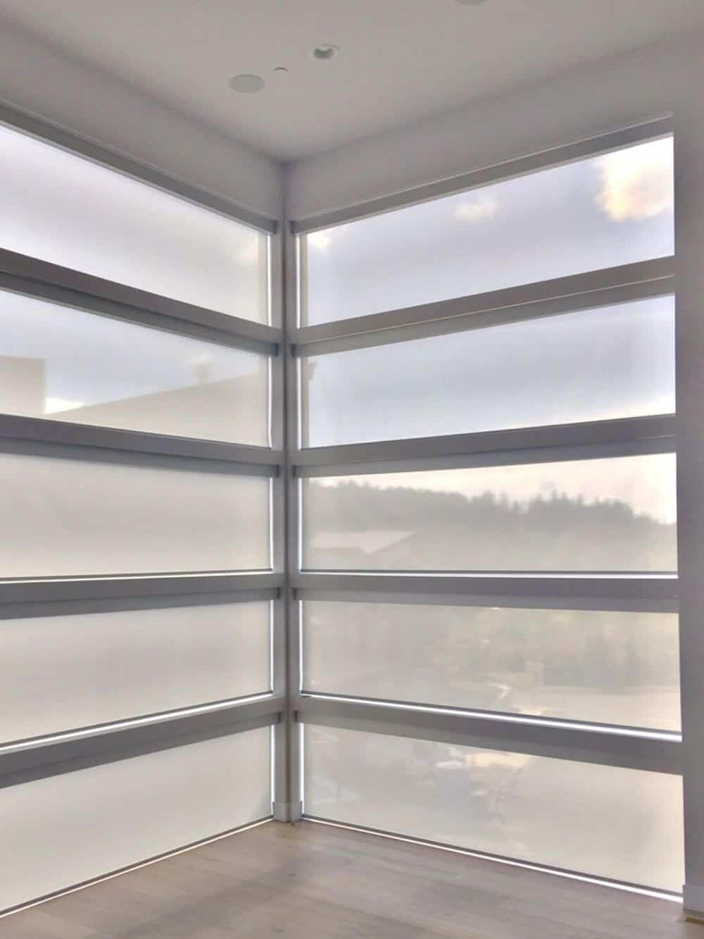 专注地看这个空的现代家庭的玻璃窗，设有太阳能窗帘。