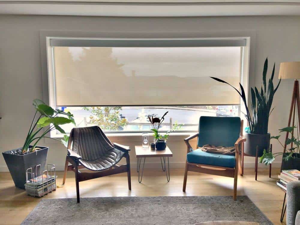 看看这个起居空间的一对座位和靠近玻璃窗的中央桌子，有一个太阳能窗帘。