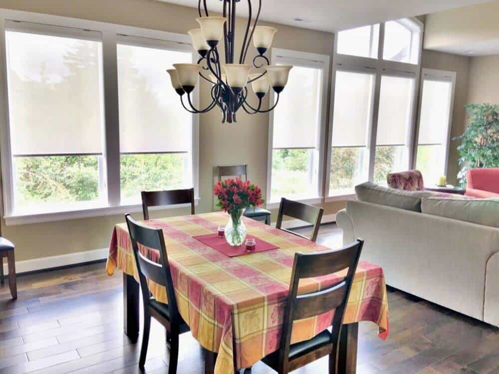 仔细看看这个家庭的四人方形餐桌，由华丽的枝形吊灯照亮。房间以硬木地板和米黄色墙壁为特色。