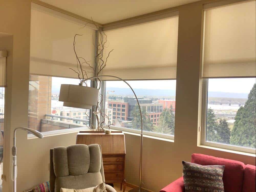 客厅里有一组时髦的座椅和一盏时髦的落地灯，周围是带遮阳罩的玻璃窗。