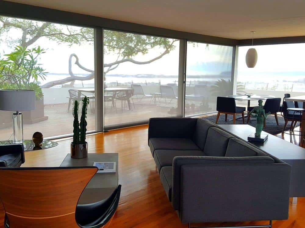 一个现代的生活空间，配有看起来绝对时尚的现代沙发套装，以及一张与生活套装完美搭配的中央桌子。房间拥有带遮阳板的大玻璃窗。