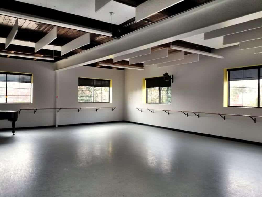 宽敞的空起居空间设有灰色地板和白色墙壁，以及定制的天花板。房间的窗户设有遮阳板。