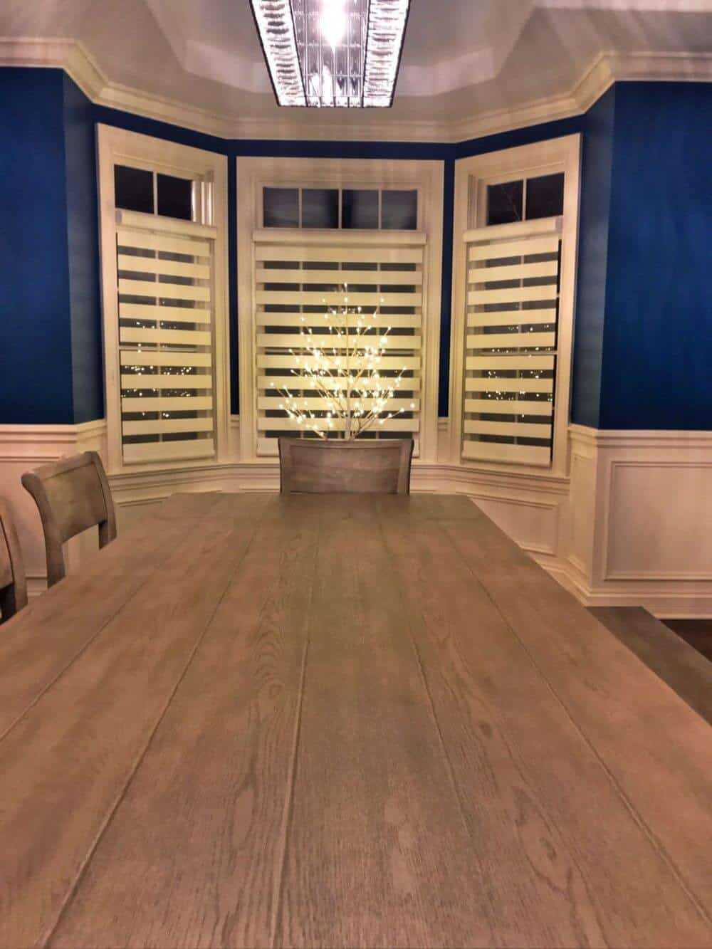 仔细看看这个木制餐桌套装与优雅的椅子。房间的特色是蓝色的墙壁和定制的天花板，以及带有过渡窗帘的窗户。