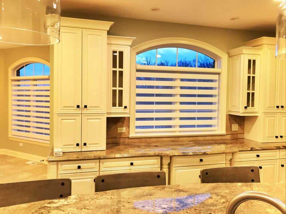 厨房拥有大理石台面的厨房柜台和中心岛。岛上还提供了一个早餐吧。有带有过渡窗帘的窗户。