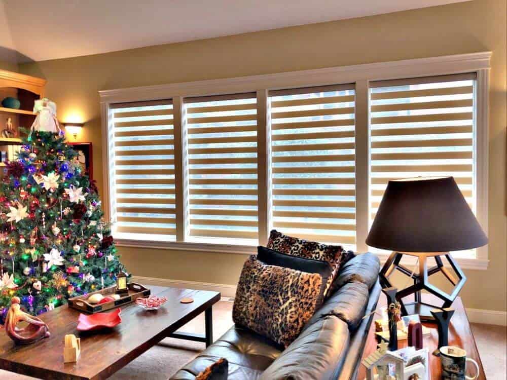 这个生活空间拥有一个优雅的皮革沙发组和一个木制的中心桌子，旁边有圣诞树装饰。住宅的窗户以过渡阴影为特色。