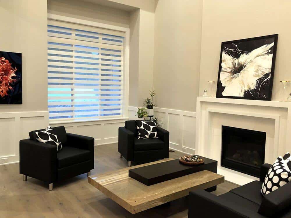 这间客厅拥有一个现代的沙发套和一个时尚的中心桌，以及一个壁炉和硬木地板。还有一扇窗户，以过渡窗帘为特色。