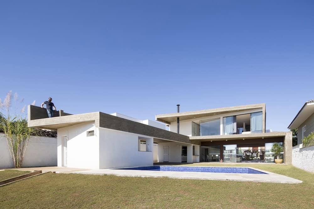 这座可爱的现代住宅采用L形设计，为后院游泳池和草坪提供了充足的空间，从高高的玻璃窗和墙壁以及二层的大型室外区域都可以欣赏到草坪。
