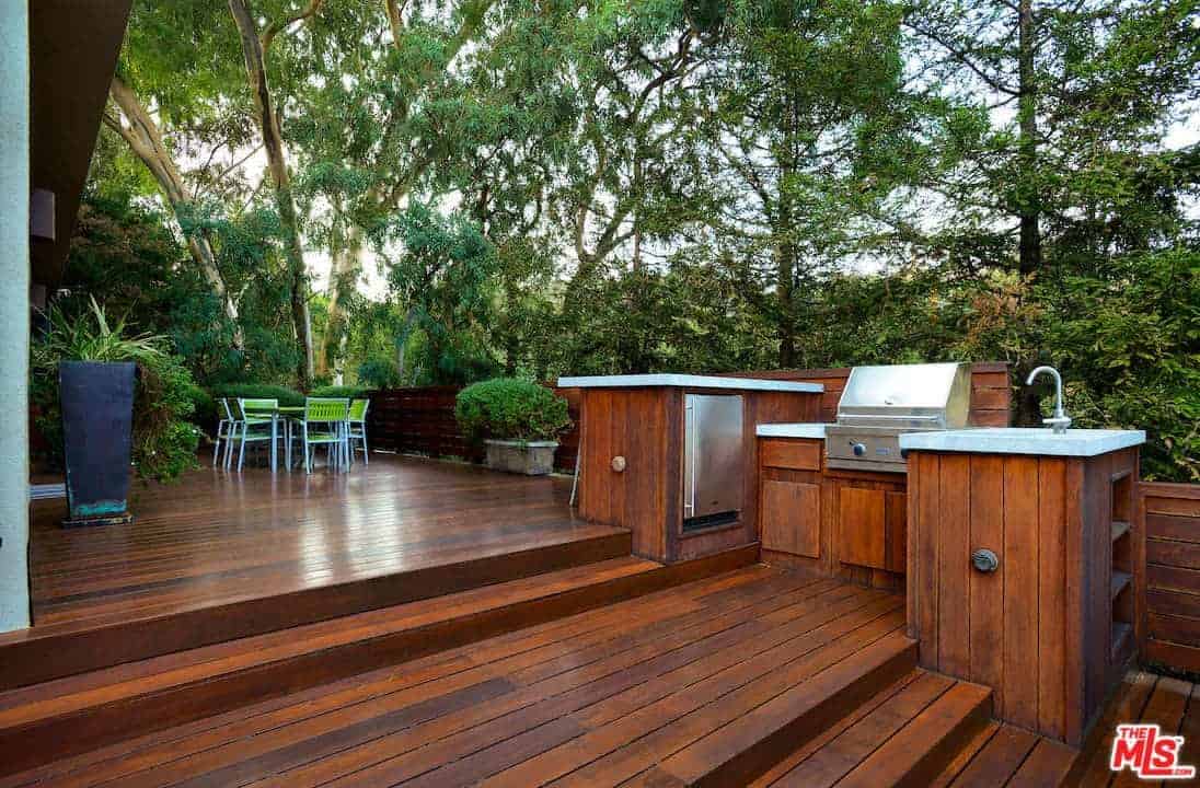 宽敞的甲板上有红木地板，与柜台和栏杆相匹配。它包括一张绿色的桌子和椅子，与周围环境融为一体。