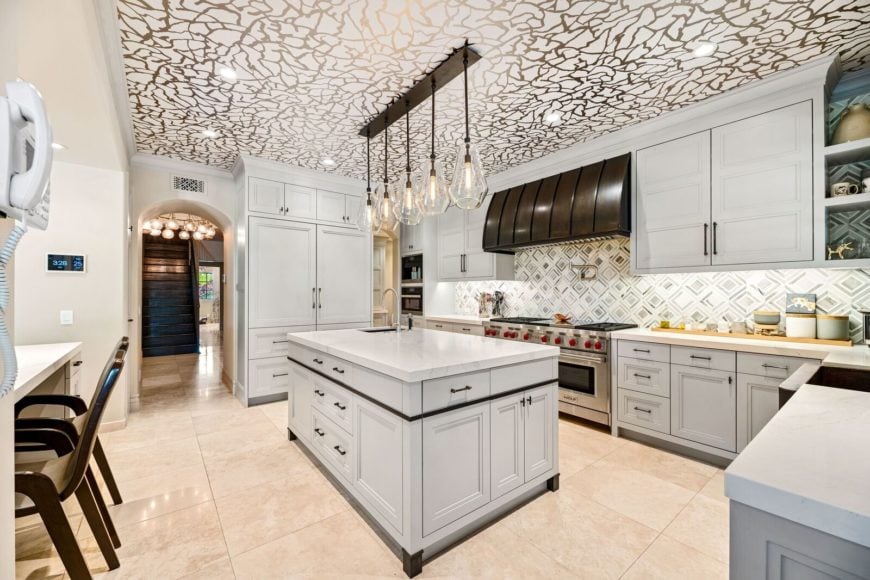 加州塔扎纳的一所大厨房曾是演员凯莉·库柯的家，天花板设计很有趣，直接来自《生活大爆炸》，地板是米黄色的瓷砖。这个空间包括一个早餐吧、大理石台面的厨房柜台和一个由一串当代吊灯照亮的中央岛台。