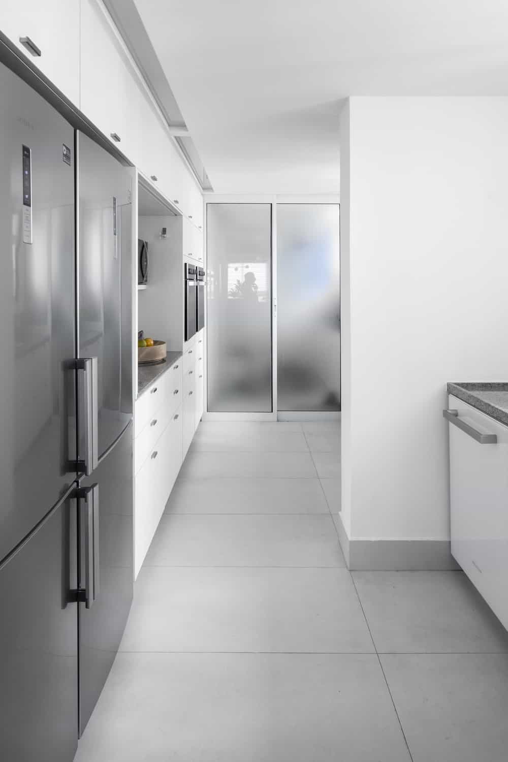 这是一个狭长的厨房，白色的橱柜使不锈钢电器脱颖而出。
