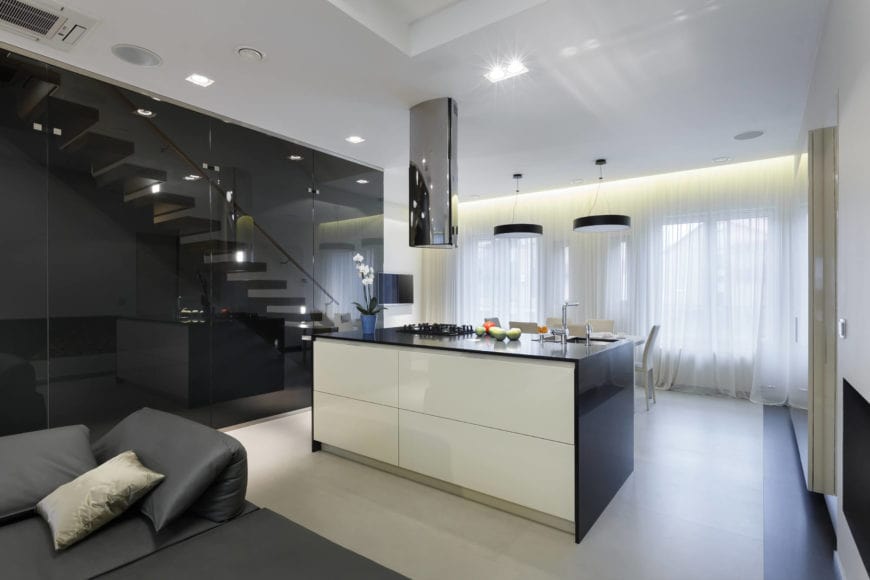 一个非常简单而光滑的厨房，在瓷砖地板上有一个极简主义的厨房吧台。它配有水槽和灶台，并配有与落地柜相匹配的镜面通风罩。