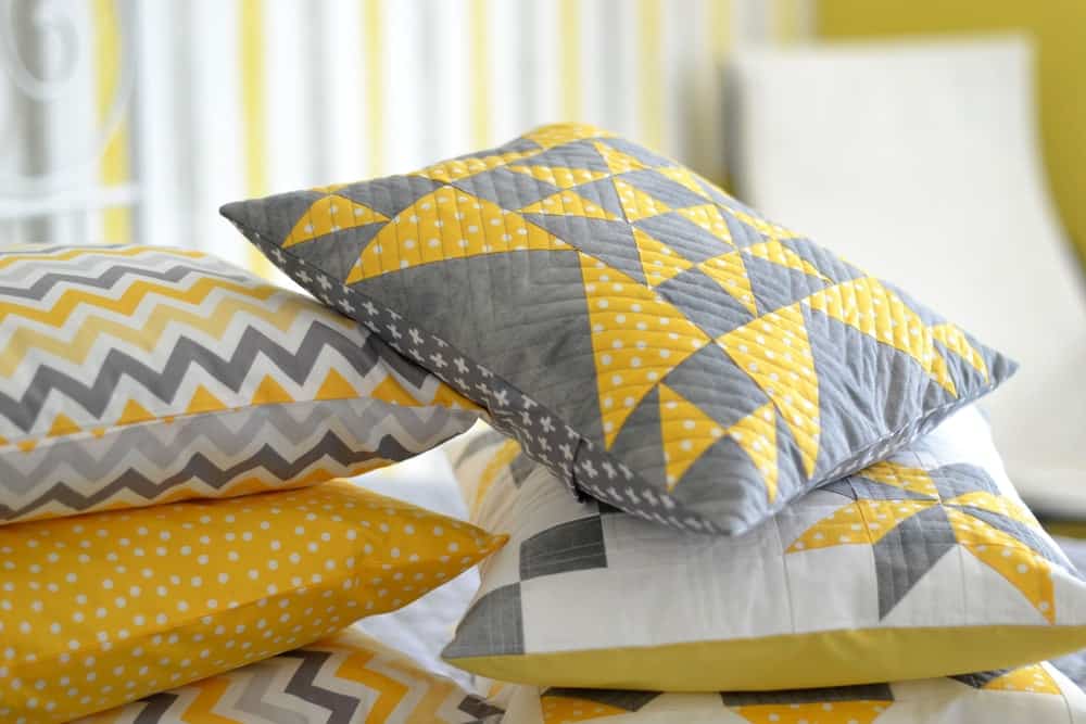 一堆抱枕，上面有不同图案的黄色床罩。