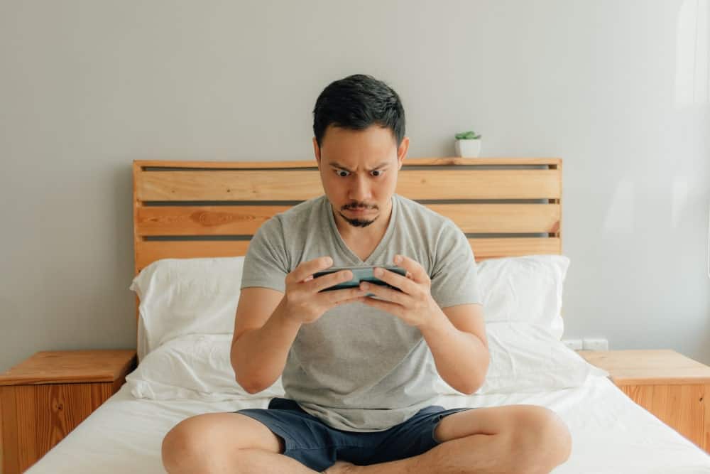 男人在床上玩手机游戏。